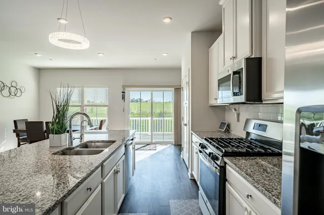 a kitchen with granite countertop a sink a counter top space appliances and cabinets
