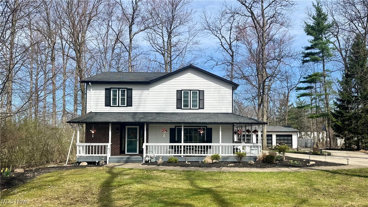 View of front of home with covered porch, roof with shingles, and a front yard