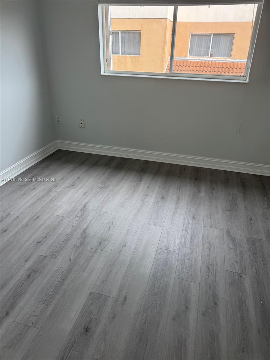 14909 Southwest 80th Street, Unit 216 Miami, FL 33193 - Photo 12 of 16 a view of an empty room with wooden floor and a window
