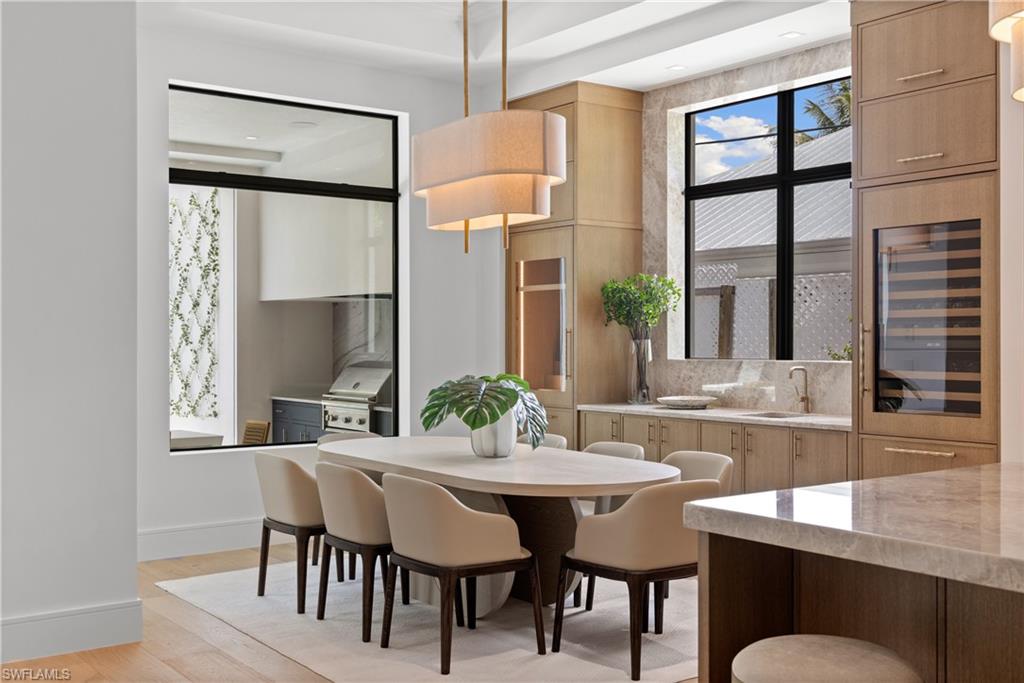 850 10th Street North Naples, FL 34102 - Photo 14 of 50 Dining room with Taj Mahal countertop and backsplash, wine refrigerator and liquor display, custom cabinetry