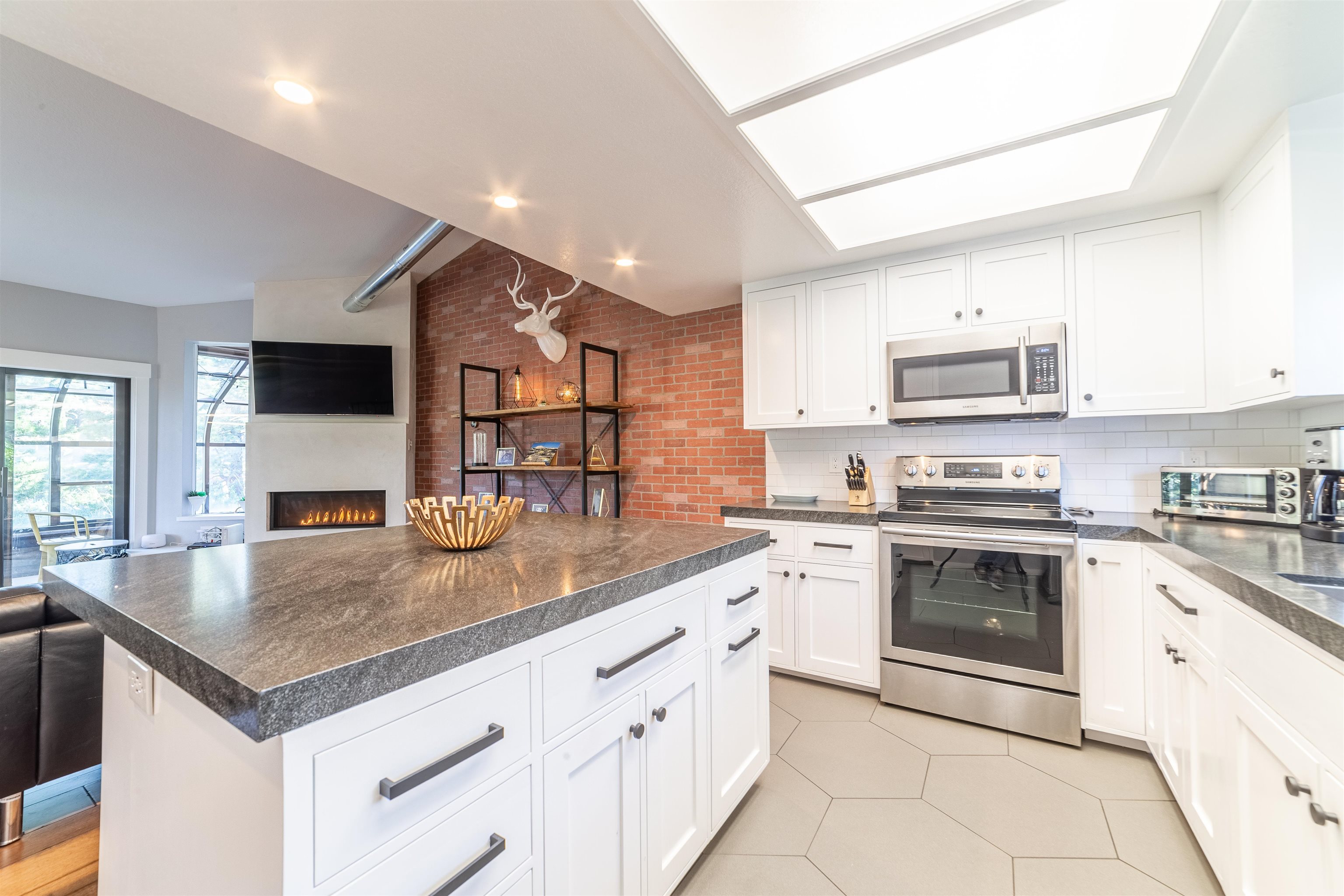 384 Joaquin Road, Unit 31 Mammoth Lakes, CA 93546 - Photo 26 of 29 Kitchen featuring appliances with stainless steel finishes, dark countertops, open floor plan, and a large fireplace