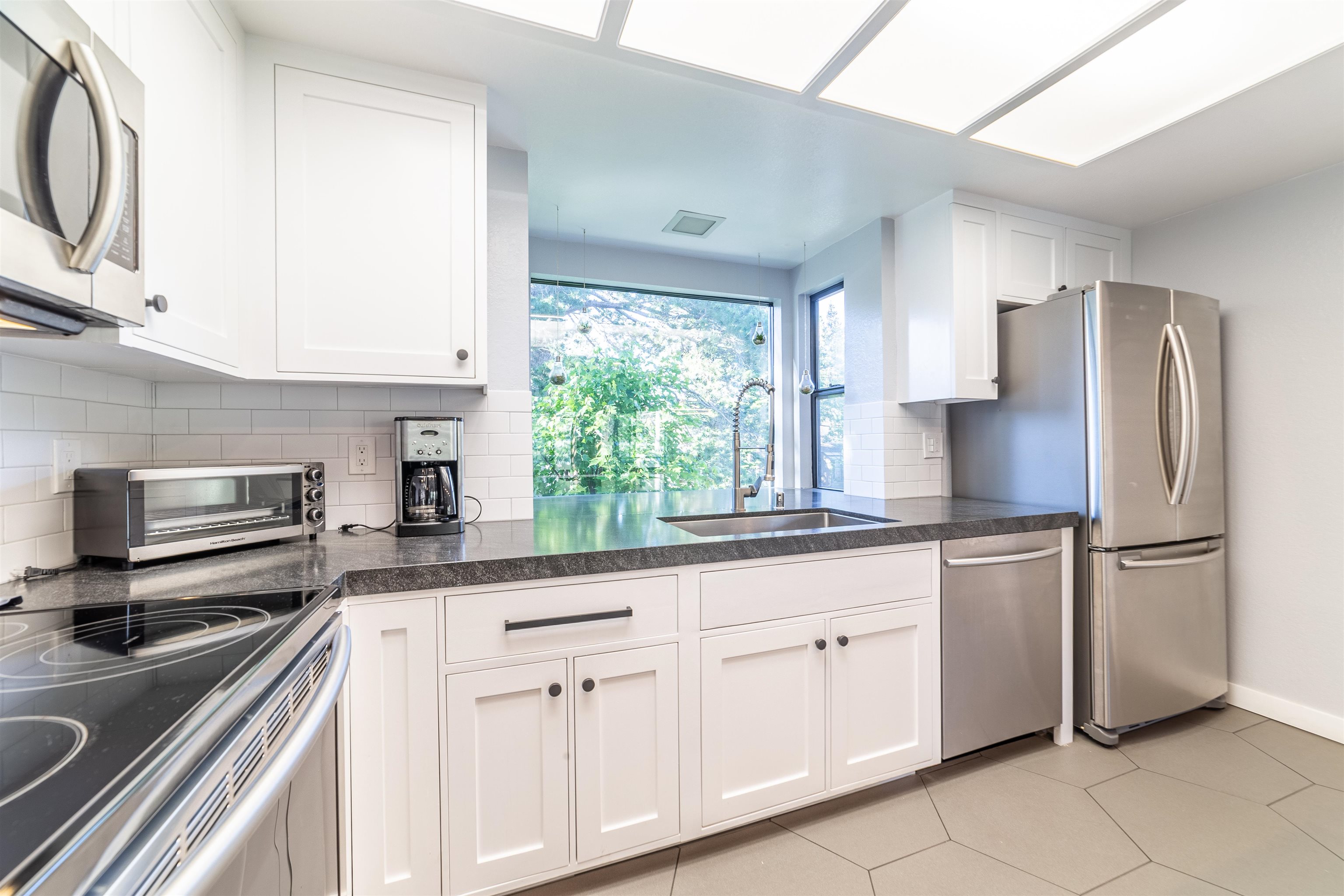 384 Joaquin Road, Unit 31 Mammoth Lakes, CA 93546 - Photo 5 of 29 Kitchen featuring appliances with stainless steel finishes, white cabinets, decorative backsplash, and dark countertops
