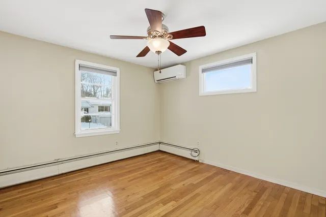 an empty room with wooden floor ceiling fan and windows