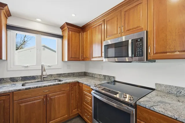 a kitchen with granite countertop a sink cabinets and stainless steel appliances