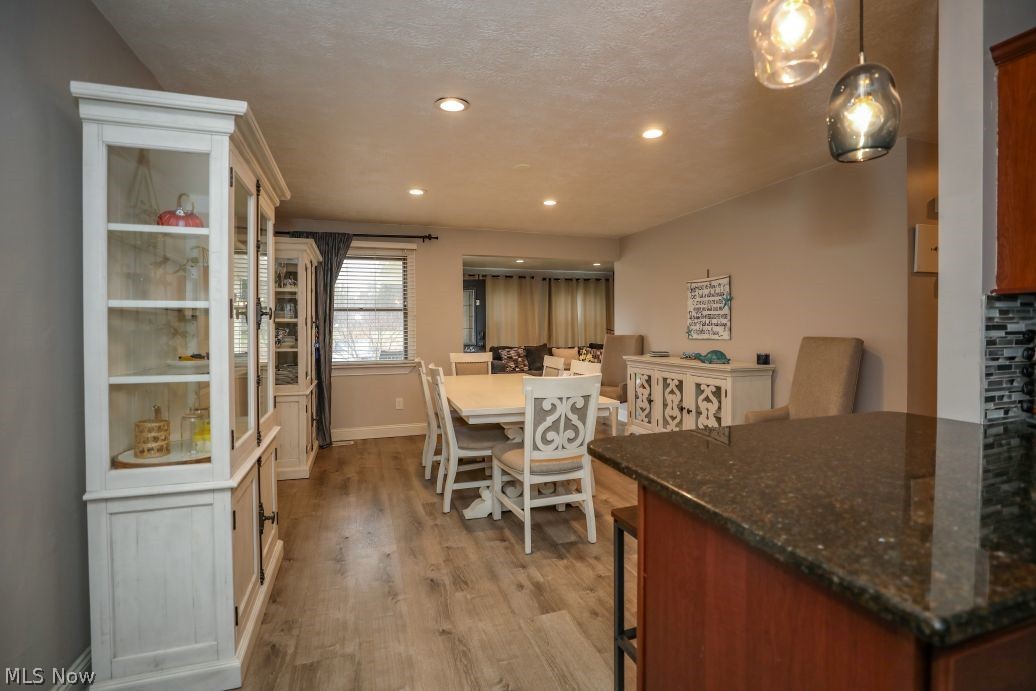 10676 Holcomb Road Newton Falls, OH 44444 - Photo 18 of 38 Kitchen featuring a kitchen breakfast bar, dark granite counters, LVT floors, and pendant lighting