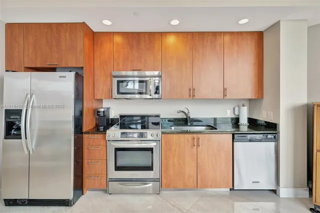 a kitchen with stainless steel appliances granite countertop a refrigerator a stove a sink and a microwave