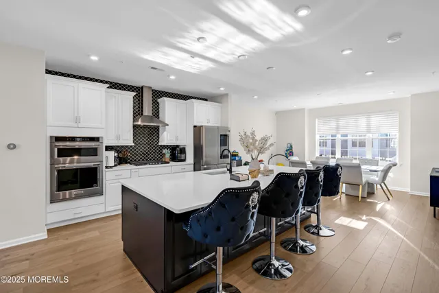 a large white kitchen with lots of counter space wooden floor and stainless steel appliances