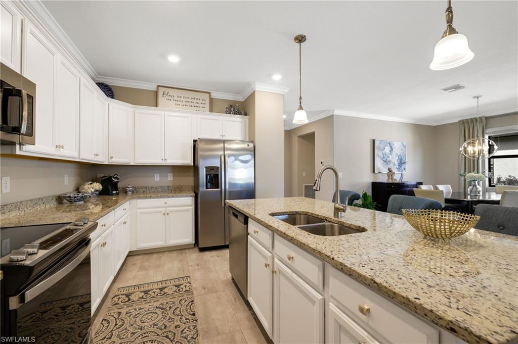 19724 The Pl Boulevard Estero, FL 33928 - Photo 15 of 36 a kitchen with a sink dishwasher a stove a refrigerator and white cabinets with wooden floor