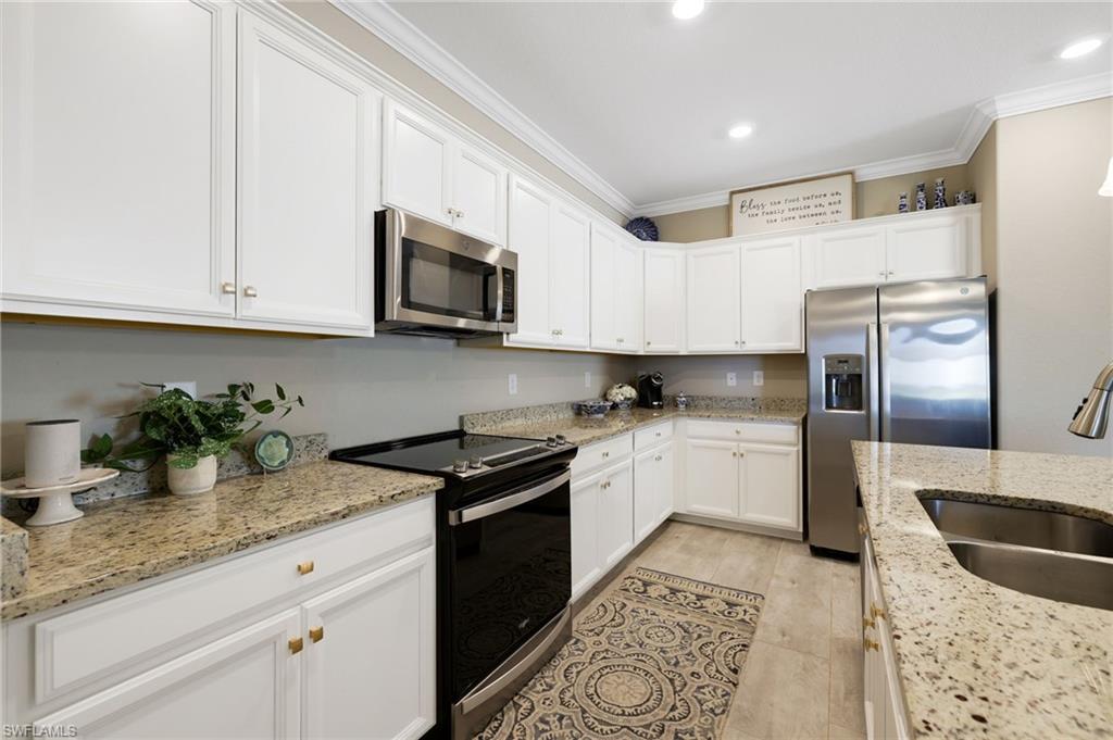 19724 The Pl Boulevard Estero, FL 33928 - Photo 16 of 36 a kitchen with granite countertop a sink stainless steel appliances and white cabinets