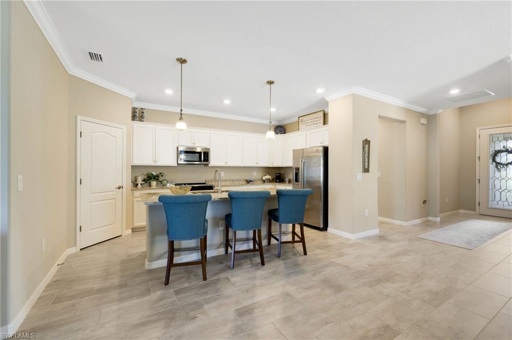 19724 The Pl Boulevard Estero, FL 33928 - Photo 19 of 36 a kitchen with stainless steel appliances kitchen island granite countertop a refrigerator a stove a sink with a dining table and chairs