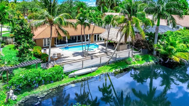 a view of a swimming pool with a garden and palm trees