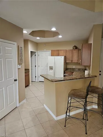 a kitchen with granite countertop a refrigerator sink and cabinets