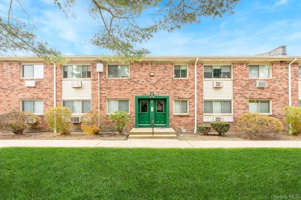 a front view of a building with a garden and plants