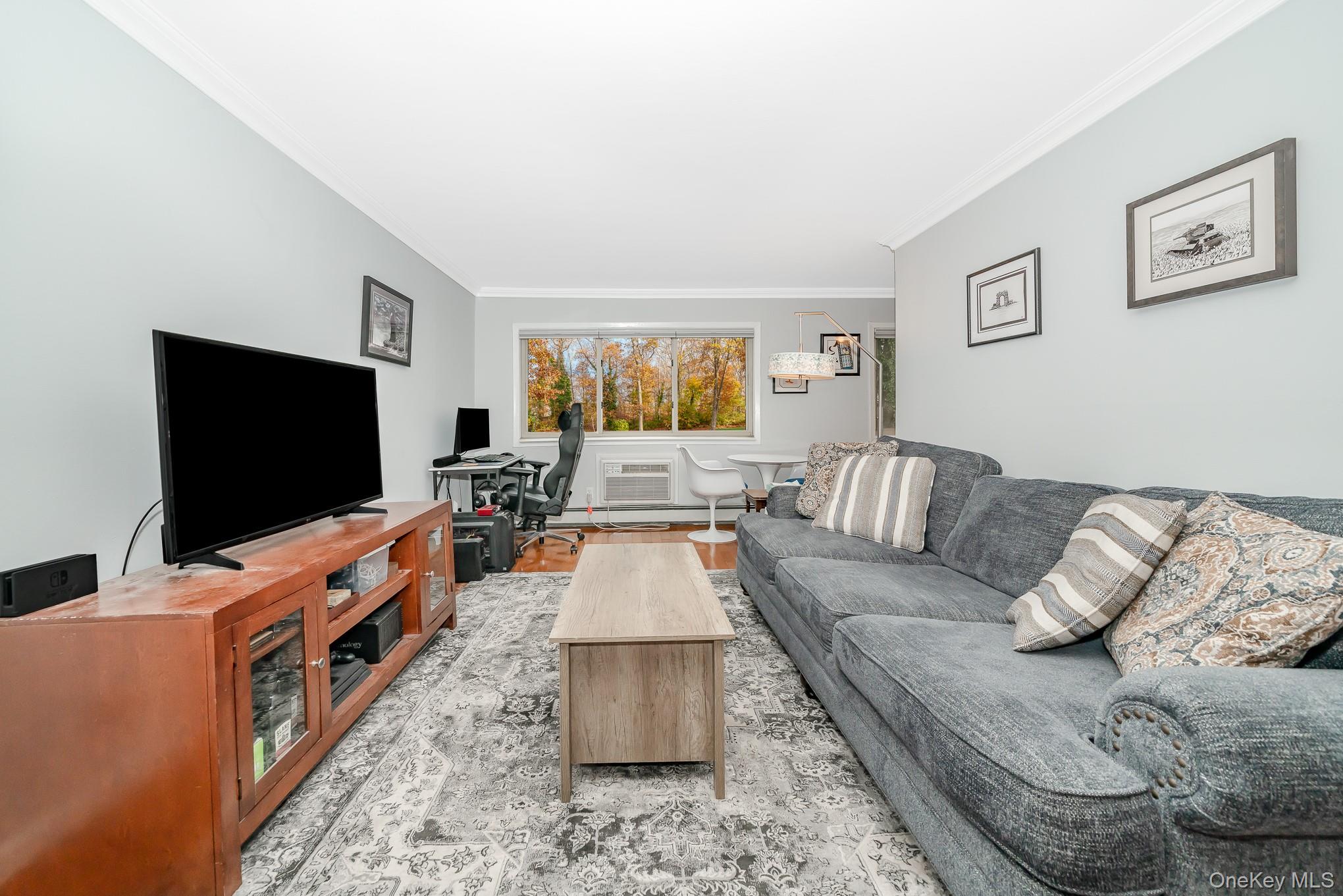 2449 F Union Boulevard, Unit 12A Islip, NY 11751 - Photo 6 of 16 Living room featuring crown molding, a desk, a wall unit AC, and wood finished floors