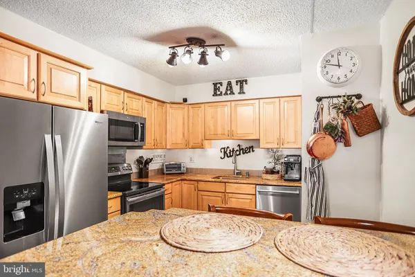 a kitchen with stainless steel appliances granite countertop a sink a stove cabinets dining table and chairs