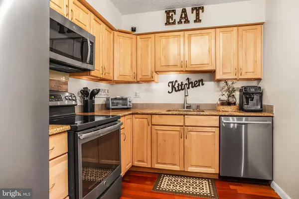 a kitchen with stainless steel appliances a sink a stove cabinets and a window