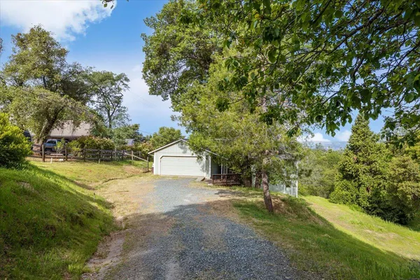 a view of a house with a yard and large tree
