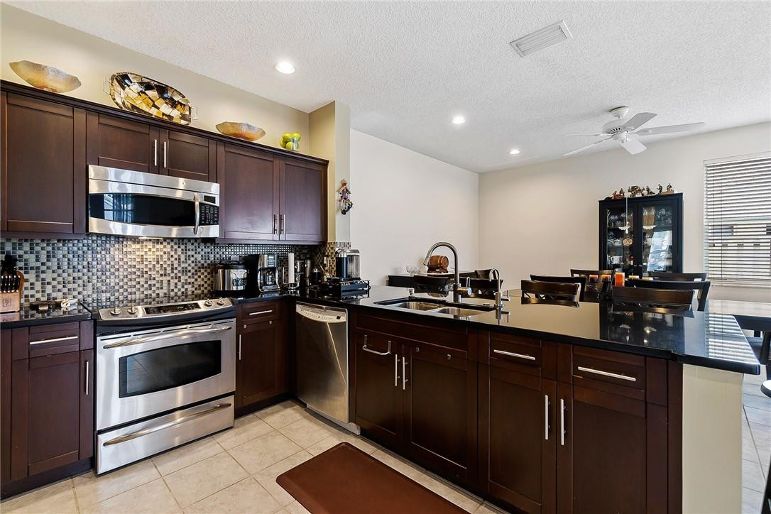 869 Briar Ridge Road Weston, FL 33327 - Photo 6 of 24 a kitchen with granite countertop a sink cabinets and stainless steel appliances