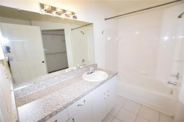 a bathroom with a granite countertop sink a mirror and a bathtub
