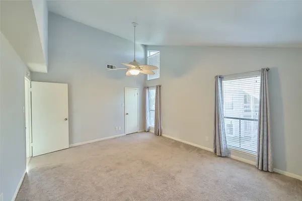 an empty room that has a chandelier fan and a window
