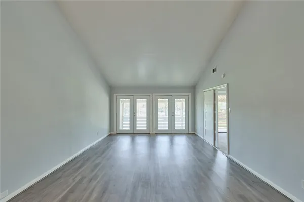 a view of an empty room with wooden floor and window