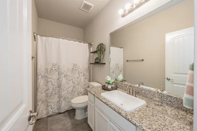 a bathroom with a granite countertop sink toilet and shower