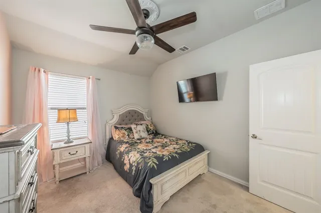 a bedroom with a bed a dresser and a flat screen tv