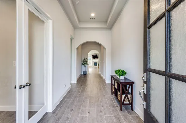a view of a hallway view with wooden floor staircase and a living room