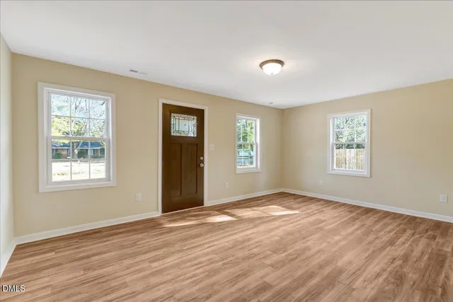 a view of an empty room with wooden floor and a window