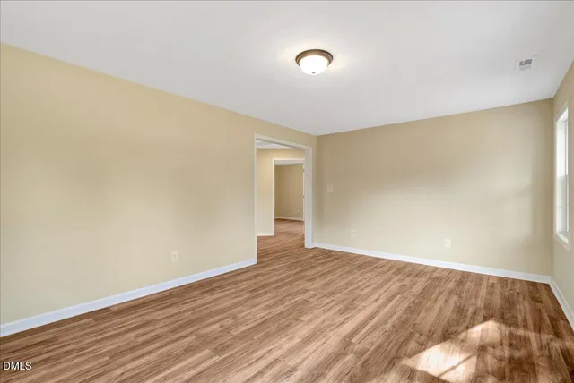 a view of an empty room with wooden floor and closet