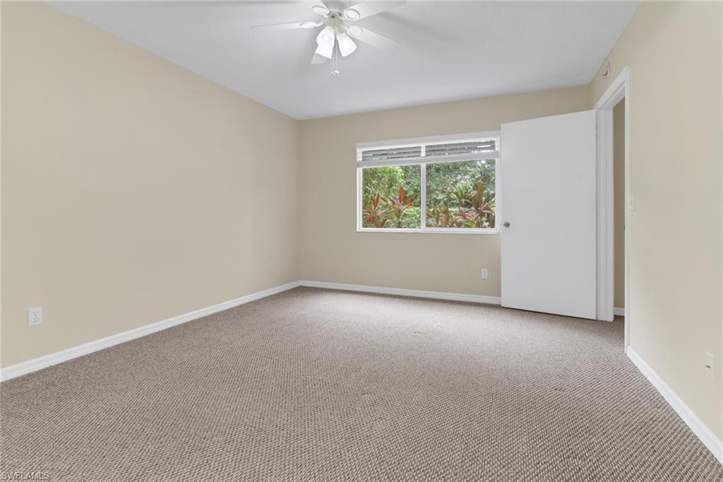 7779 Jewel Lane, Unit 103 Naples, FL 34109 - Photo 14 of 26 an empty room with windows and chandelier fan