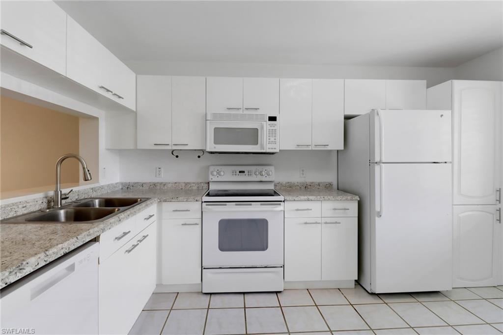 7779 Jewel Lane, Unit 103 Naples, FL 34109 - Photo 4 of 26 a white kitchen with sink and white stainless steel appliances