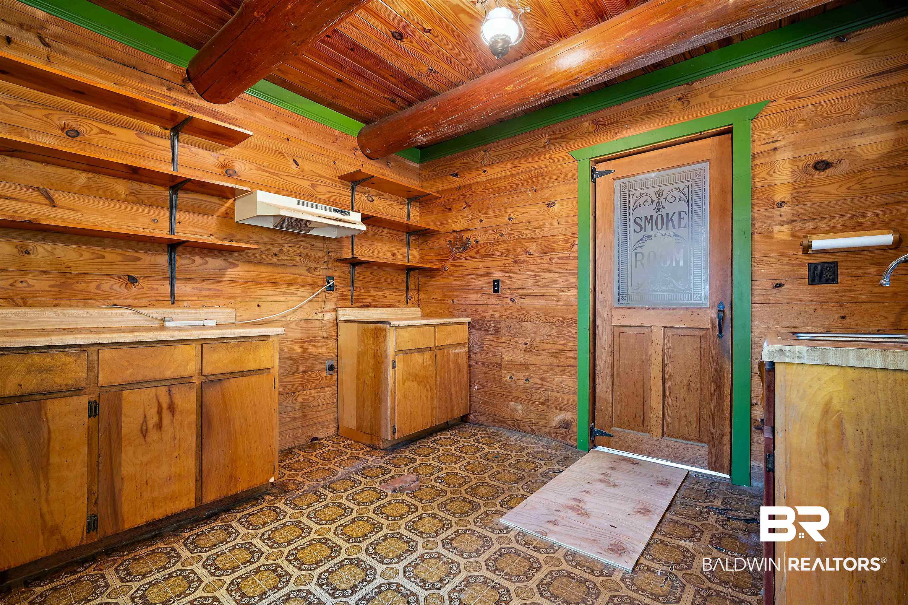 11236 Wren Avenue Fairhope, AL 36532 - Photo 12 of 35 Kitchen featuring a wooden ceiling with exposed beams, brown cabinetry, wooden walls, under cabinet range hood, and dark flooring