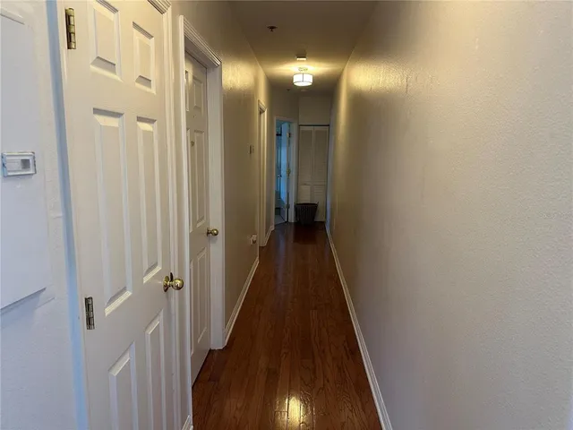 a view of a hallway with wooden floor and a bathroom