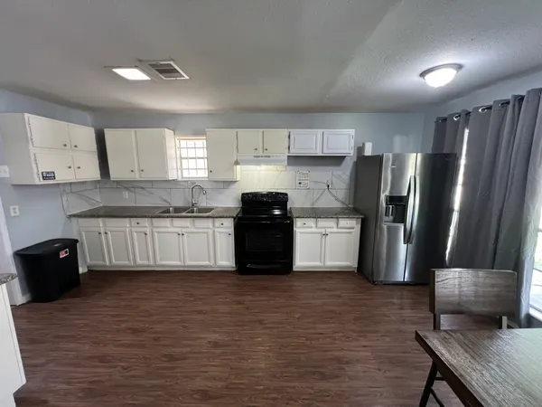 a kitchen with granite countertop a refrigerator oven a sink a stove a dining table and chairs