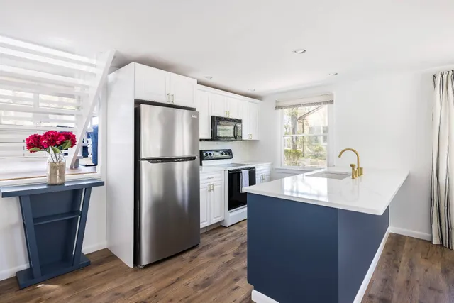 a kitchen with stainless steel appliances granite countertop a refrigerator a sink dishwasher and wooden cabinets with wooden floor