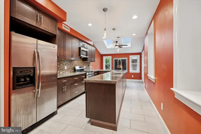 a kitchen with stainless steel appliances granite countertop a refrigerator a sink and a stove