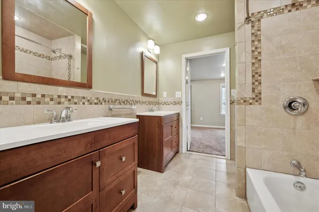 a bathroom with a sink vanity granite tub shower and a mirror