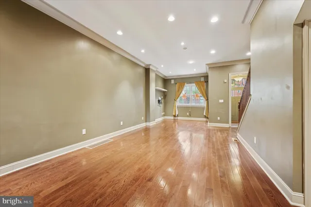 an empty room with wooden floor and window