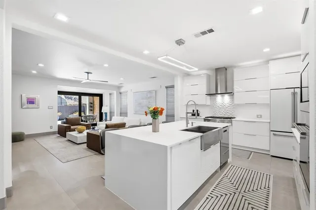 a kitchen that has a lot of white cabinets a sink and stainless steel appliances