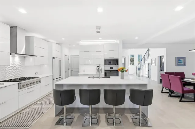a large kitchen with a dining table chairs stainless steel appliances and cabinets