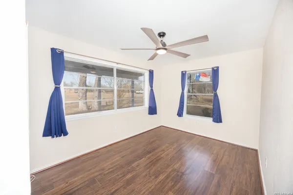 a view of an empty room with a window and wooden floor