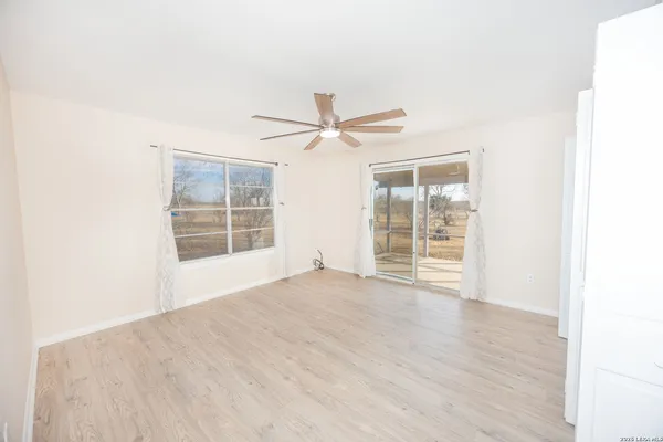 an empty room with wooden floor fan and windows