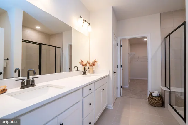 a spacious bathroom with a double vanity sink a mirror and a shower