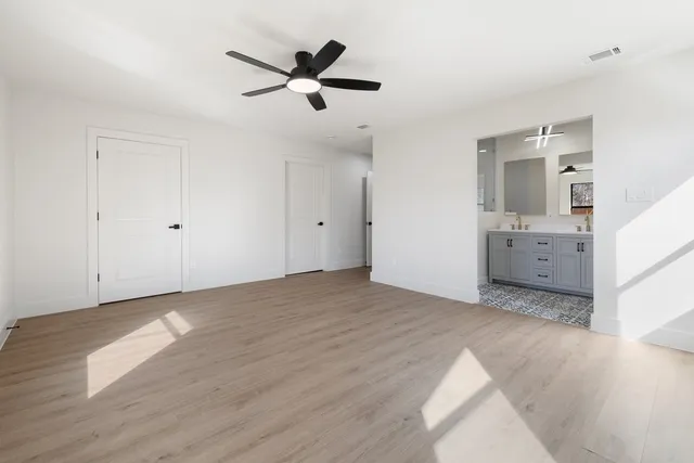 an empty room with wooden floor ceiling fan and windows