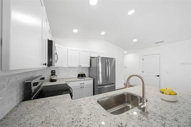 a kitchen with stainless steel appliances granite countertop a refrigerator sink and stove