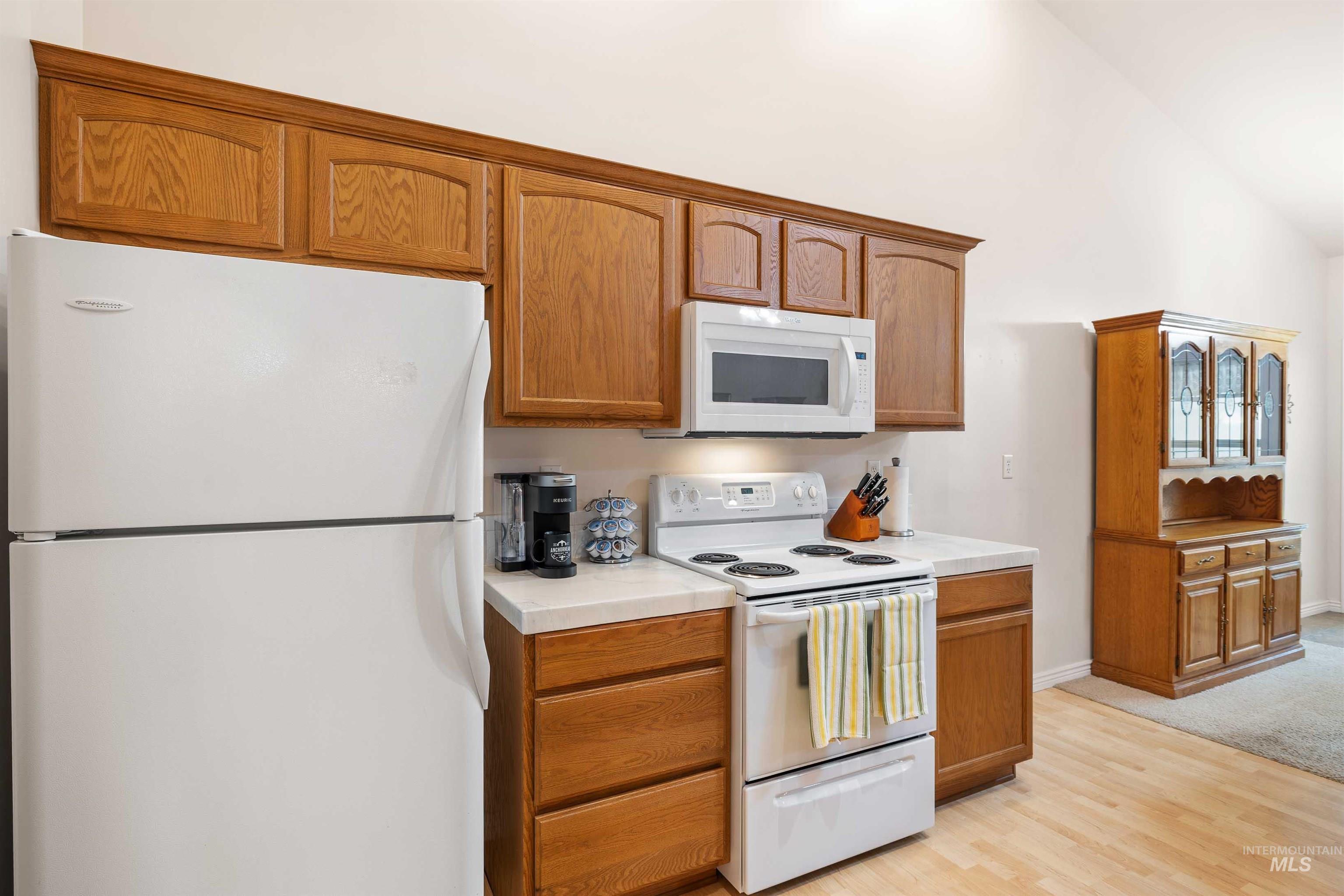 215 Los Lagos Twin Falls, ID 83301 - Photo 10 of 30 Kitchen featuring white appliances, light countertops, light wood-style floors, and brown cabinetry