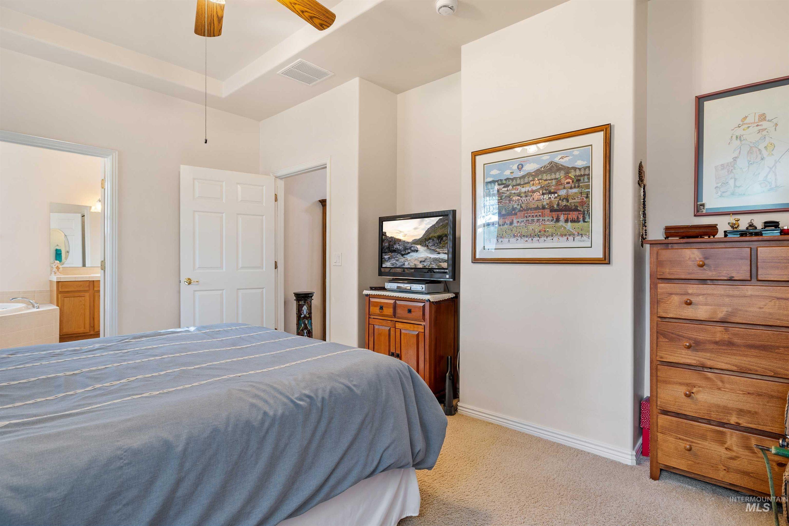 215 Los Lagos Twin Falls, ID 83301 - Photo 13 of 30 Bedroom with light colored carpet, a ceiling fan, and ensuite bathroom