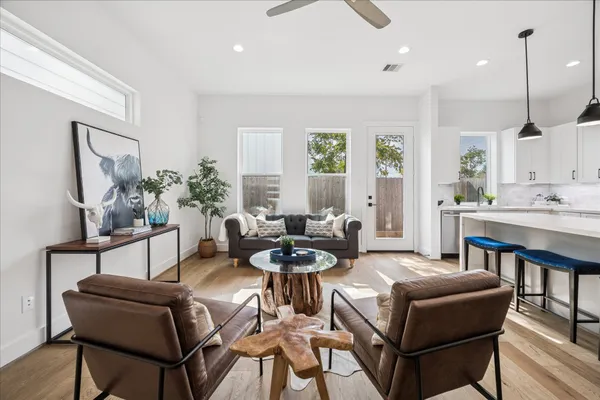 a living room with furniture kitchen view and a chandelier