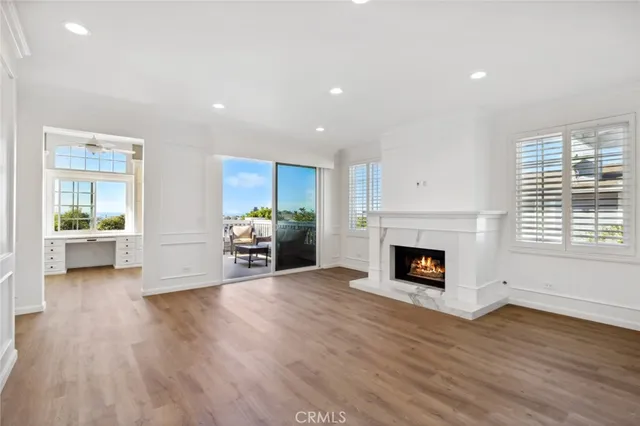 a view of a livingroom with a fireplace a window and wooden floor